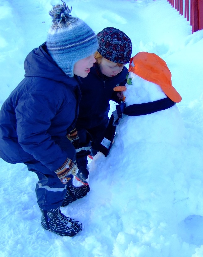 Thomas and Leo decorating snowman with vegs, hat and scarf